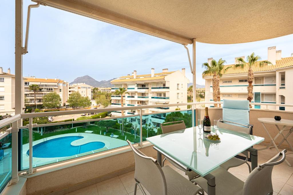 a balcony with a table and chairs and a swimming pool at Estrella 2 penthouse in L’Alfàs del Pi