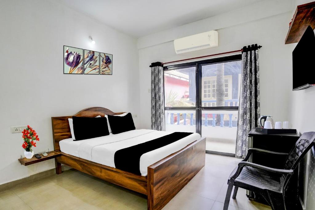 een slaapkamer met een bed en een groot raam bij Super Hotel O Calangute Beach St. Anthony's Chapel Formerly Hotel Sun & Sea in Goa
