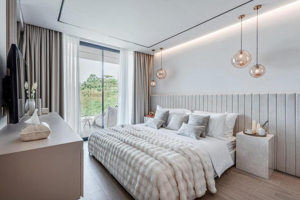 a white bedroom with a large bed and a window at Brand new Luxury 2 BR Villa CASA COCO LAUBANA in Uluwatu