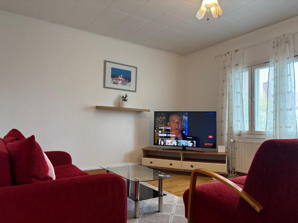 un soggiorno con una tv e due sedie rosse di Malmi Home a Vaasa