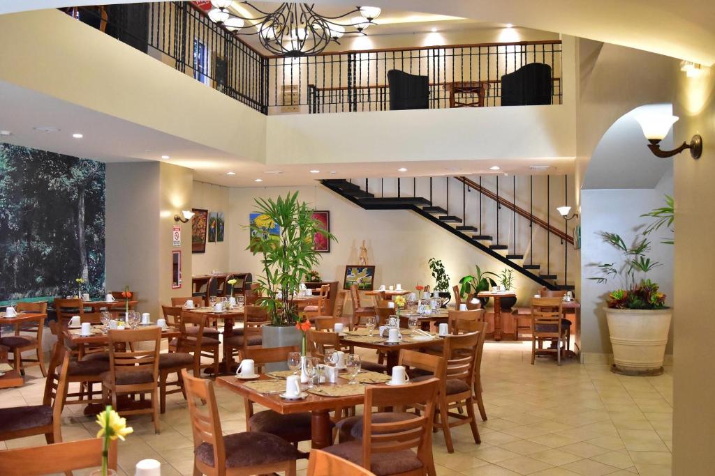 un restaurante con mesas y sillas de madera y una escalera en Sleep Inn Paseo Las Damas, en San José