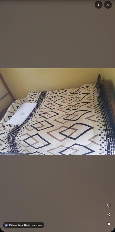 a bed with a black and white comforter at Robeck's Guest House in Gatunga