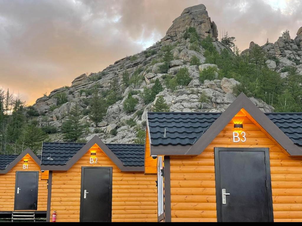 a row of wooden cabins in front of a mountain at Ko Terelj Resort in Yoliin Hural