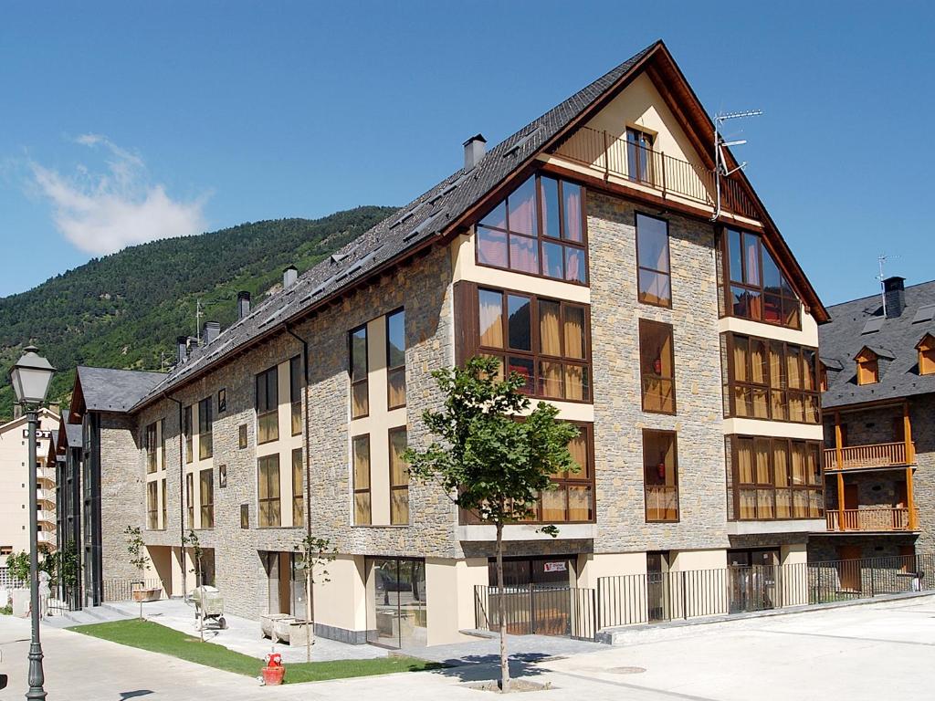 a large brick building with a mountain in the background at Aparthotel Nou Vielha in Vielha