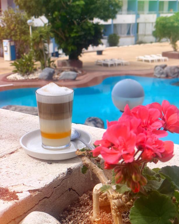 a cup of coffee sitting on a table next to flowers at Sissy Tenerife Apartman in San Miguel de Abona
