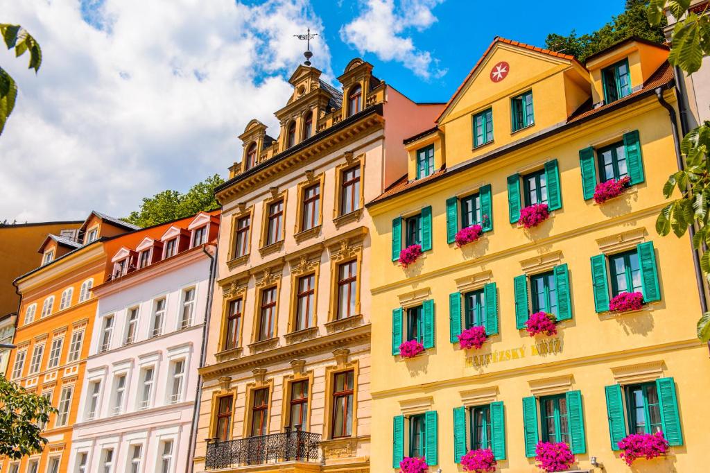 a row of colorful buildings with flowers in the windows at Hotel Maltezský Kříž in Karlovy Vary