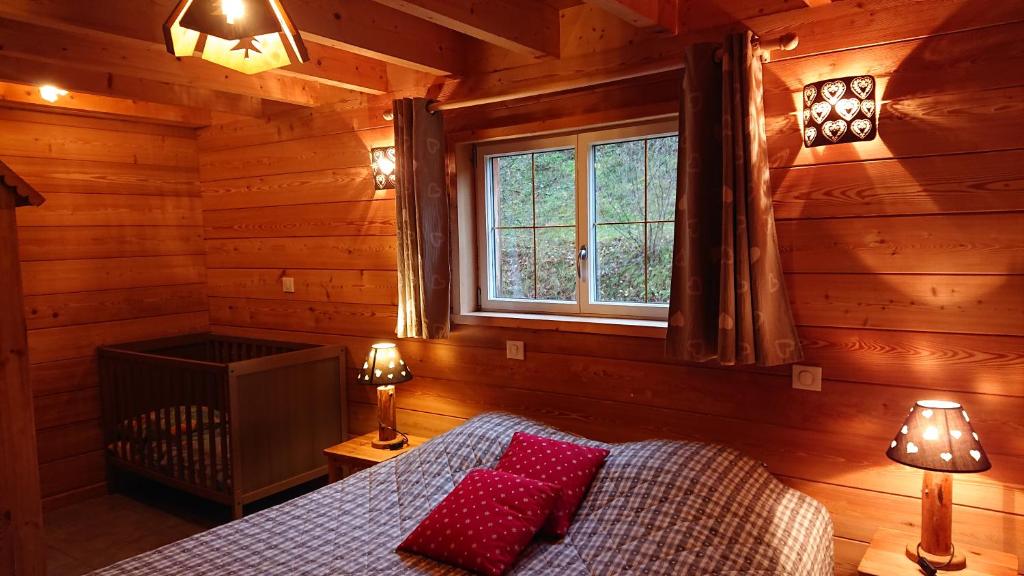 een slaapkamer met een bed met rode kussens en een raam bij Au Solé in Basse-sur-le-Rupt