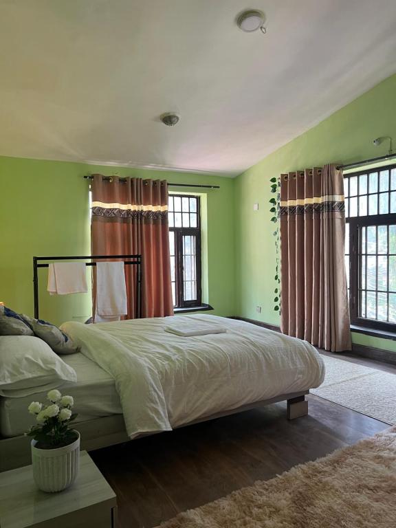 a bedroom with a large bed with green walls and windows at The newa villa homestay in Bākhri Kharka