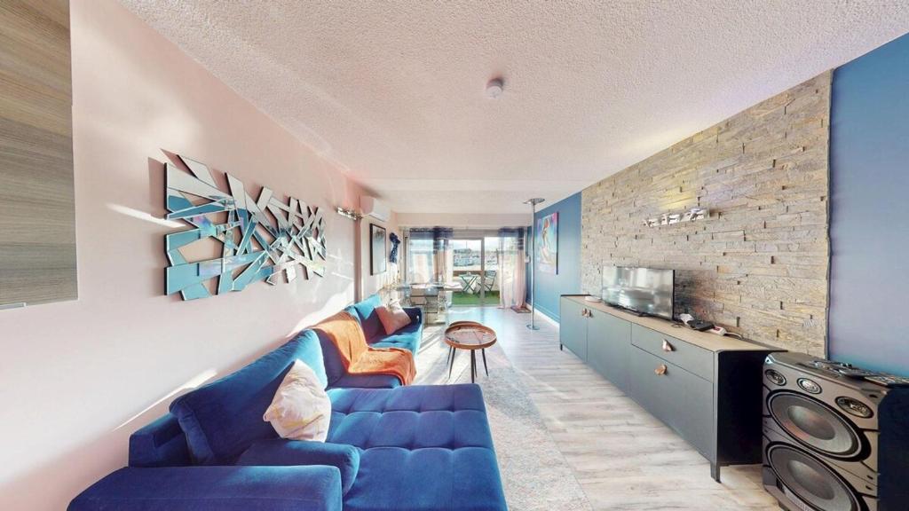 - un salon avec un canapé bleu et un mur en briques dans l'établissement Le Melrose Port Nature 5 Village Naturiste Cap d'Agde, au Cap d'Agde