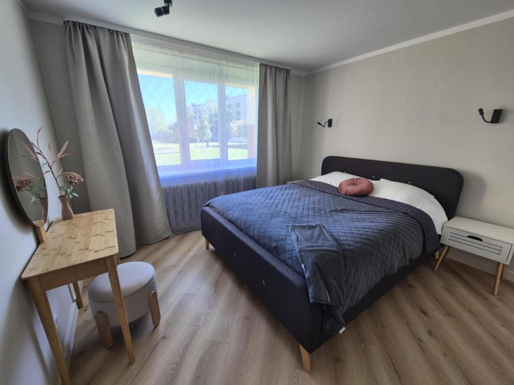 Un dormitorio con una cama y un escritorio y una ventana. en Jūras 3, en Ventspils