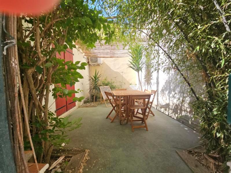 un patio avec une table, des chaises et des arbres dans l'établissement La Tiny House YourHostHelper, à Narbonne