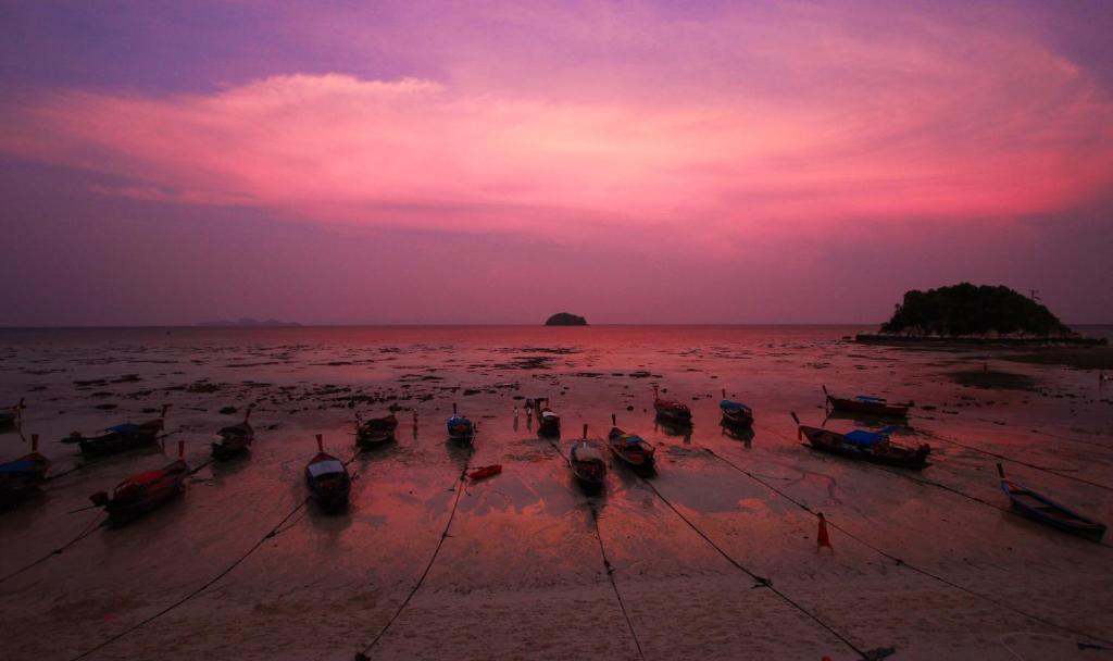 a group of boats on the beach at sunset at Cabana Lipe Beach Resort in Ko Lipe