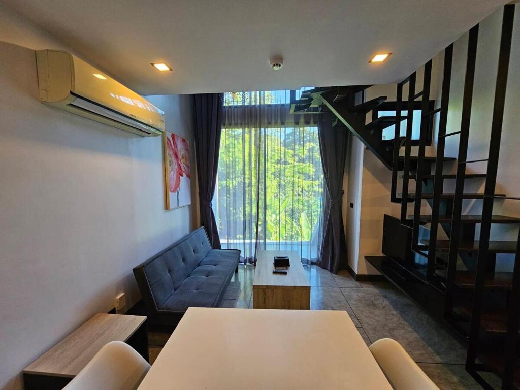 Una sala de estar con una escalera y un sofá. en Modern Naiharn Beach Duplex Apartment, en Rawai Beach