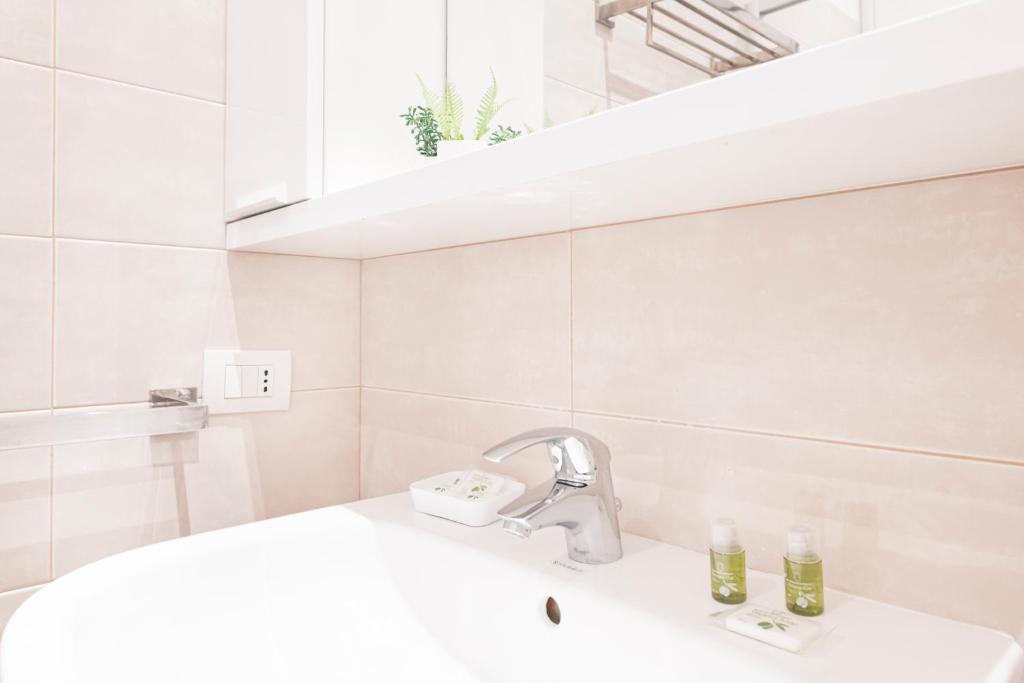 biała łazienka z umywalką i lustrem w obiekcie Magic flat in Duomo by Easylife w Mediolanie