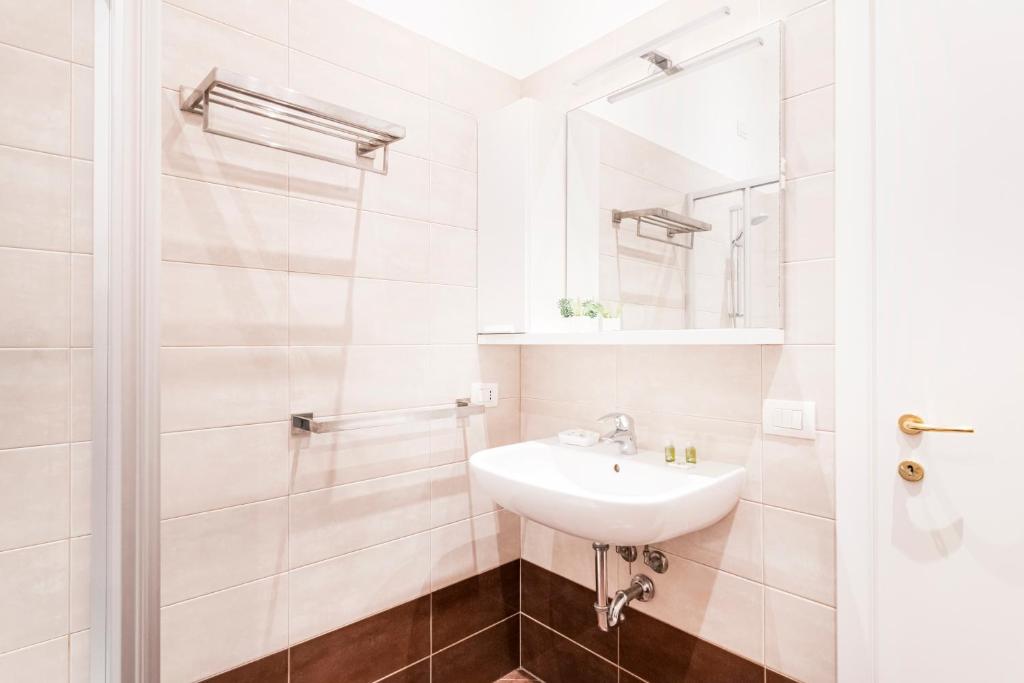 biała łazienka z umywalką i lustrem w obiekcie Magic flat in Duomo by Easylife w Mediolanie
