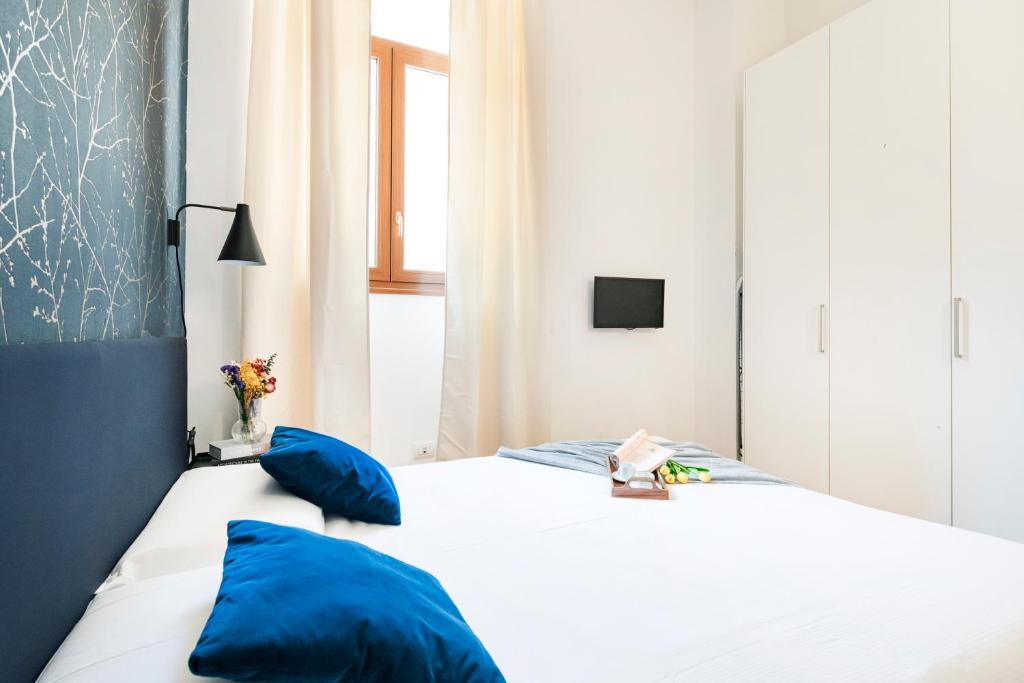 sypialnia z białym łóżkiem z niebieskimi poduszkami w obiekcie Magic flat in Duomo by Easylife w Mediolanie
