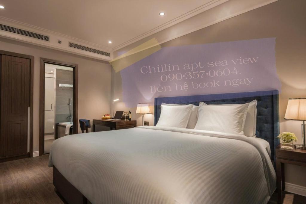 a bedroom with a large bed with a sign on the wall at Lux Chillin APT - Căn Hộ Hướng Biển Đà Nẵng in Danang