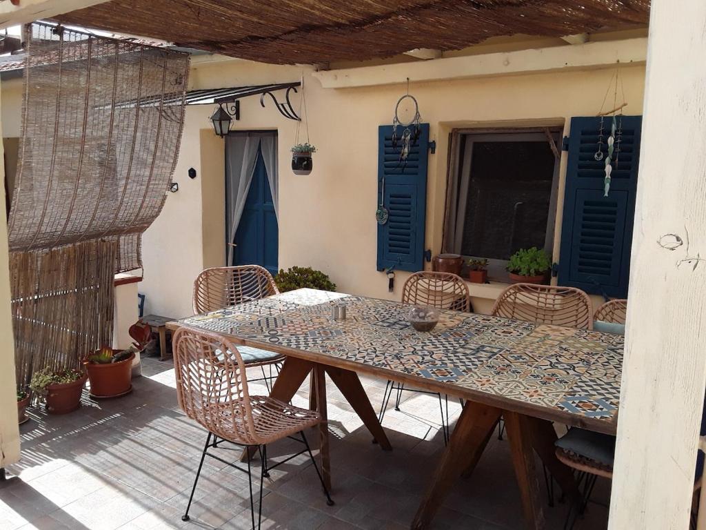 a table and chairs on a patio with blue shutters at Maison de Hameau in Breil-sur-Roya