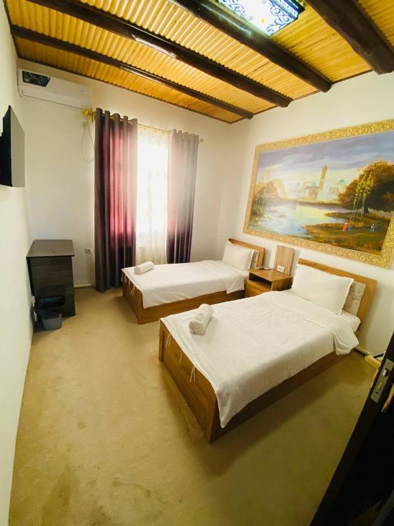 a bedroom with two beds and a painting on the wall at Afsona guest house in Bukhara