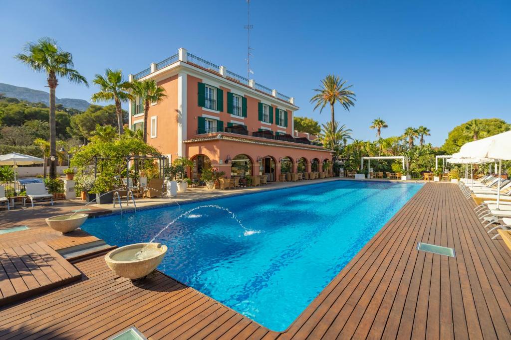 a swimming pool in front of a house at Hotel MR Les Rotes in Denia