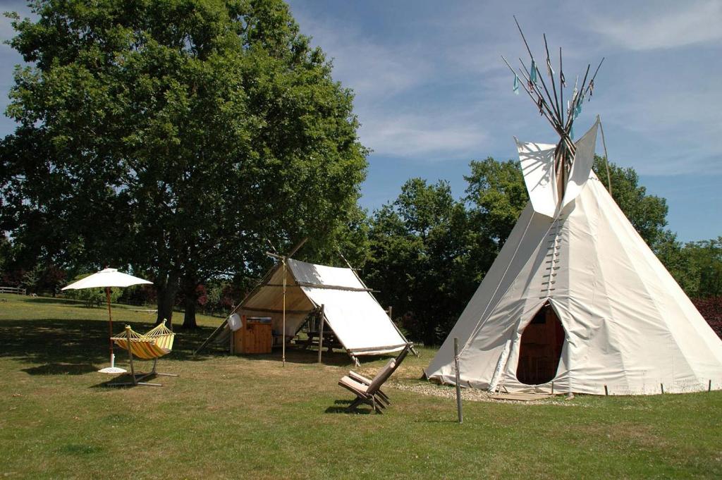 un tipi et une tente dans un champ dans l'établissement camping roussel, à Saint-Paul-dʼEspis