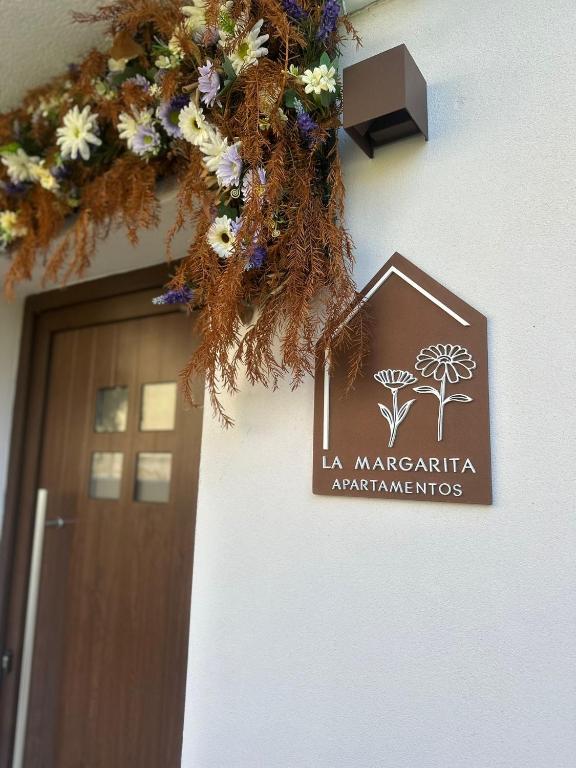 a sign on the side of a building with a door at Apartamentos La Margarita in Santillana del Mar