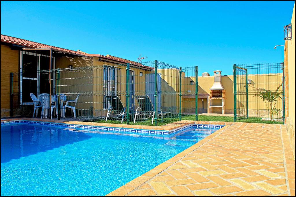 a fence around a swimming pool next to a house at Bungalow Curro Pareja 131 in Conil de la Frontera