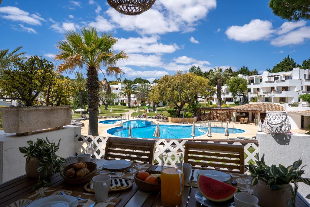 a table with fruit and juice on a balcony with a swimming pool at Luxury Beach House Apartment - Golf & Tennis Court & Pool View in Albufeira