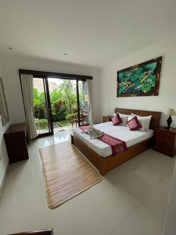 una camera da letto con un letto e una grande finestra di Nugraha Guesthouse 1 ad Ubud