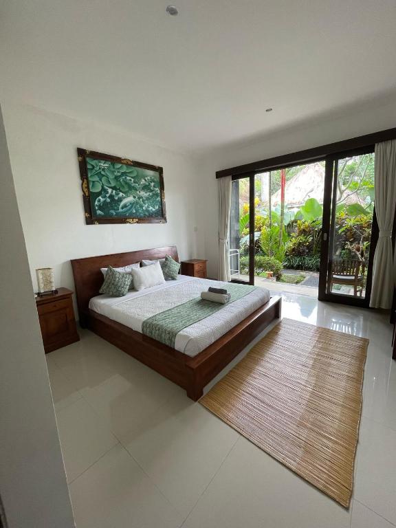 una camera da letto con un letto e una grande finestra di Nugraha Guesthouse 1 ad Ubud