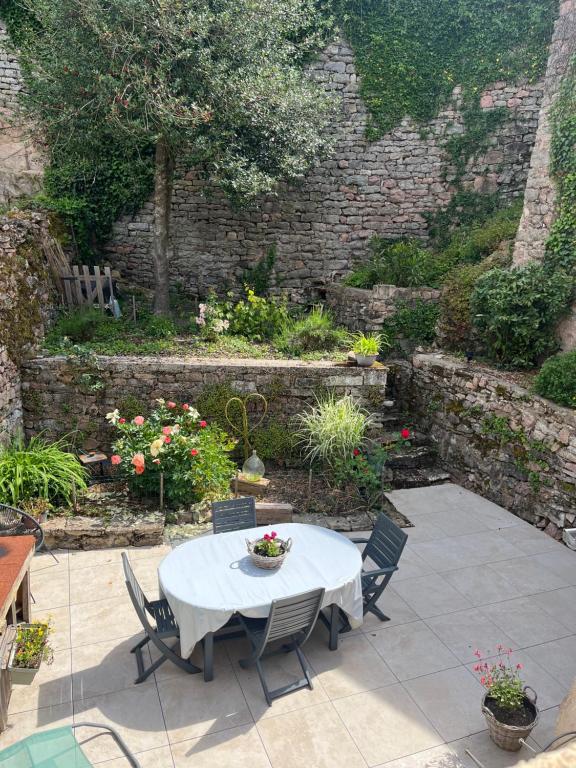 a patio with a table and chairs and a stone wall at Maison cosy en plein centre ville in Semur-en-Auxois