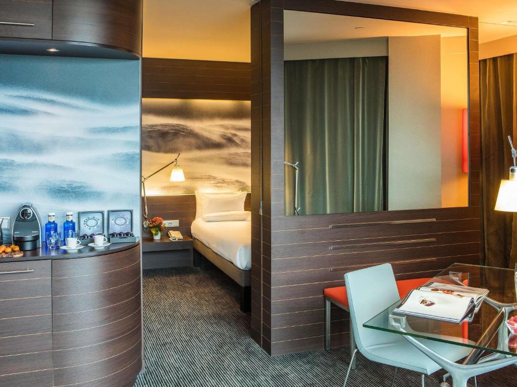 a hotel room with a bed and a desk and a table at Novotel Barcelona City in Barcelona