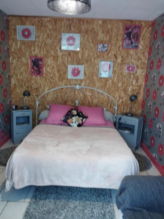 - une chambre avec un lit et des photos sur le mur dans l'établissement Chambre agréable au fond du jardin, à Sancoins