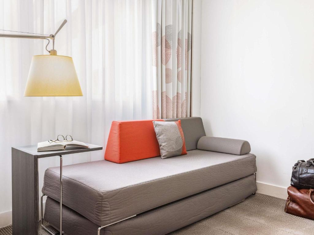 a room with a couch with a lamp and a table at Novotel Lugano Paradiso in Lugano
