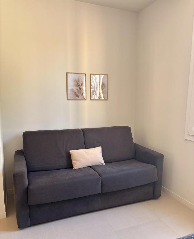 - un canapé bleu dans un salon avec deux photos dans l'établissement Studio cosy Le Vismara, à Nice