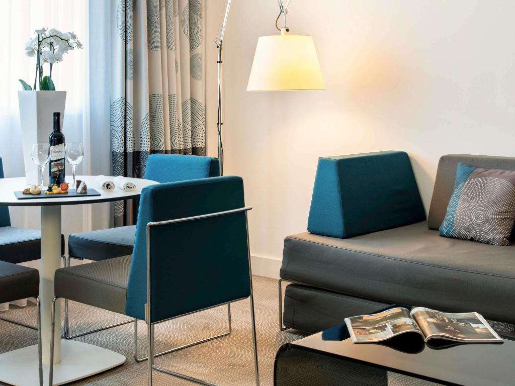 a living room with a couch and a table and chairs at Novotel Lugano Paradiso in Lugano