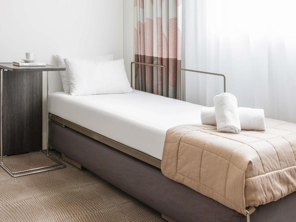 a bed with white sheets and pillows on it at Novotel Lugano Paradiso in Lugano
