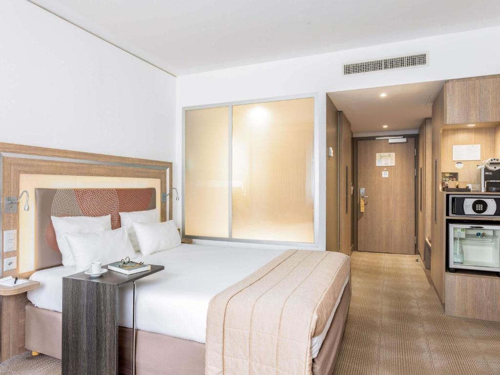 a hotel room with a large bed and a kitchen at Novotel Lugano Paradiso in Lugano