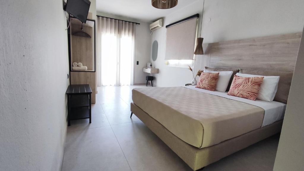 une chambre avec un grand lit blanc avec des oreillers roses dans l'établissement Nostos Studios Golden Beach, à Chrysi Ammoudia