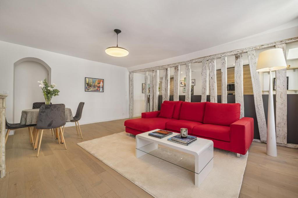 un salon avec un canapé rouge et une table dans l'établissement Ecarlate, à Paris