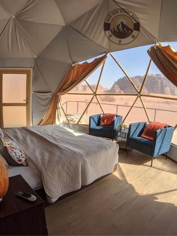 a bedroom with a bed and two chairs in a tent at WADI RUM DESERt MOON in Wadi Rum
