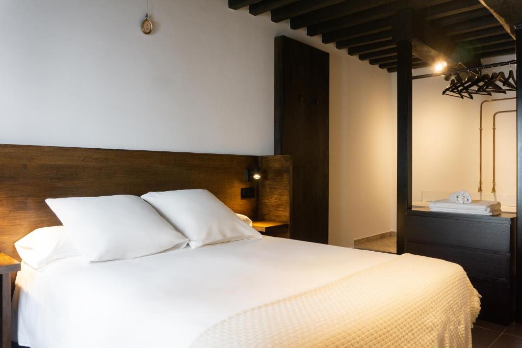 a bedroom with a white bed with a wooden headboard at La Antigua Fonda Relator in Hervás