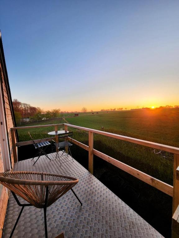 un coucher de soleil sur un porche avec un banc et une table dans l'établissement Le refuge des Châtaigniers à 10min d'Etretat, à Criquetot-lʼEsneval