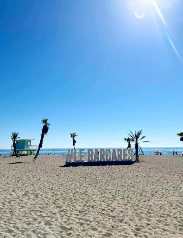 - une plage avec des palmiers et un panneau sur celle-ci dans l'établissement Ecrin du Sud, au Barcarès