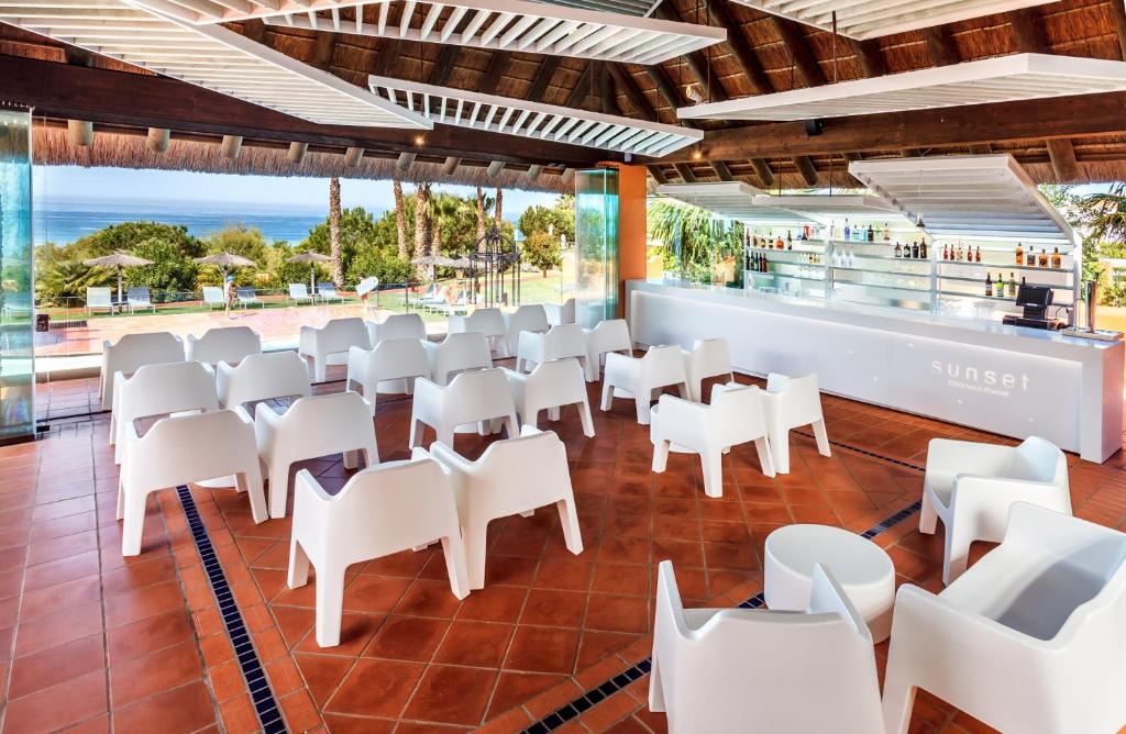 a restaurant with white chairs and a view of the ocean at Royal Hideaway Sancti Petri in Chiclana de la Frontera