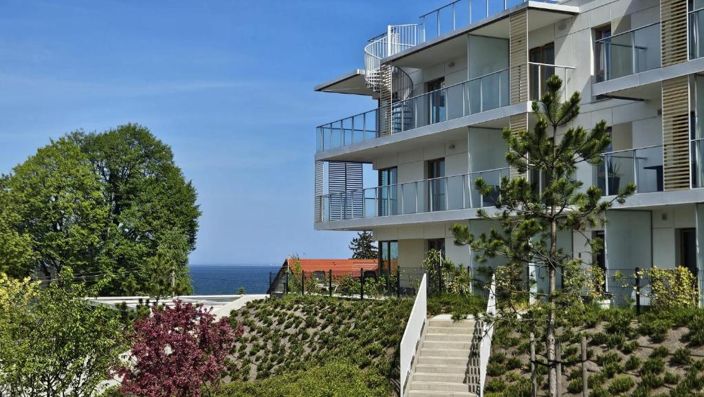 an apartment building with stairs and the ocean in the background at Mechelinki, Apartament z ogródkiem, widokiem na morze i aneksem kuchennym in Mechelinki