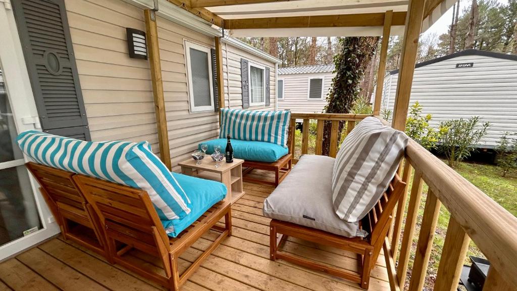 - une terrasse couverte avec 2 chaises sur une terrasse en bois dans l'établissement MOBIL-HOME HAUT DE GAMME - PROCHE MER - 3 Chambres - Dressing, à Piriac-sur-Mer