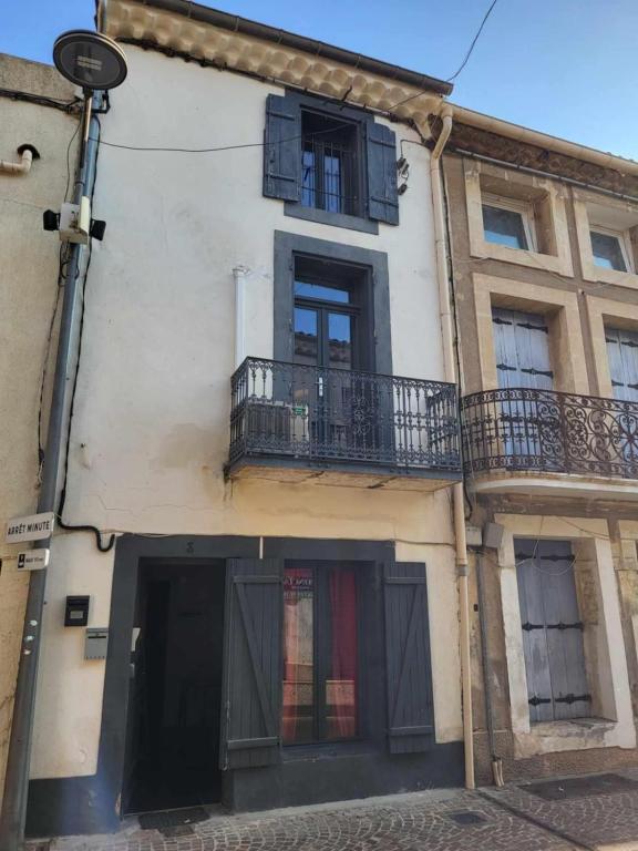 - un bâtiment blanc avec un balcon et une porte dans l'établissement Maison La Terre du Midi à Sérignan, à Sérignan