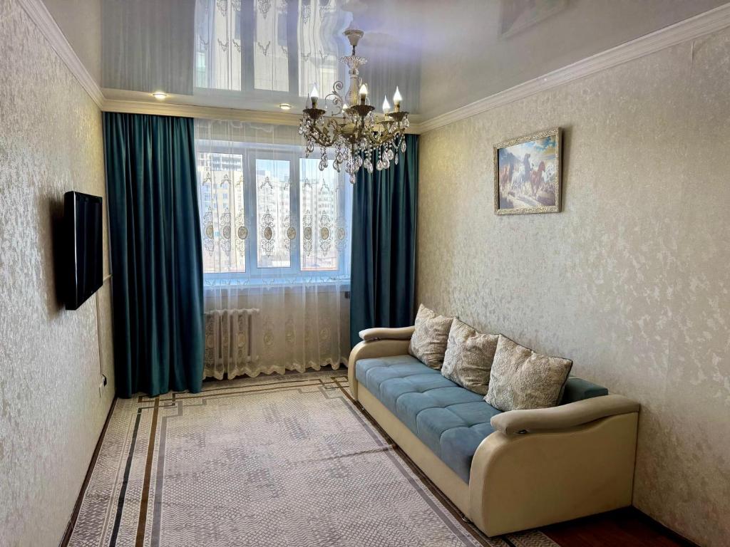 a living room with a blue couch and a chandelier at 2-х ком кв в районе Жаннур in Astana