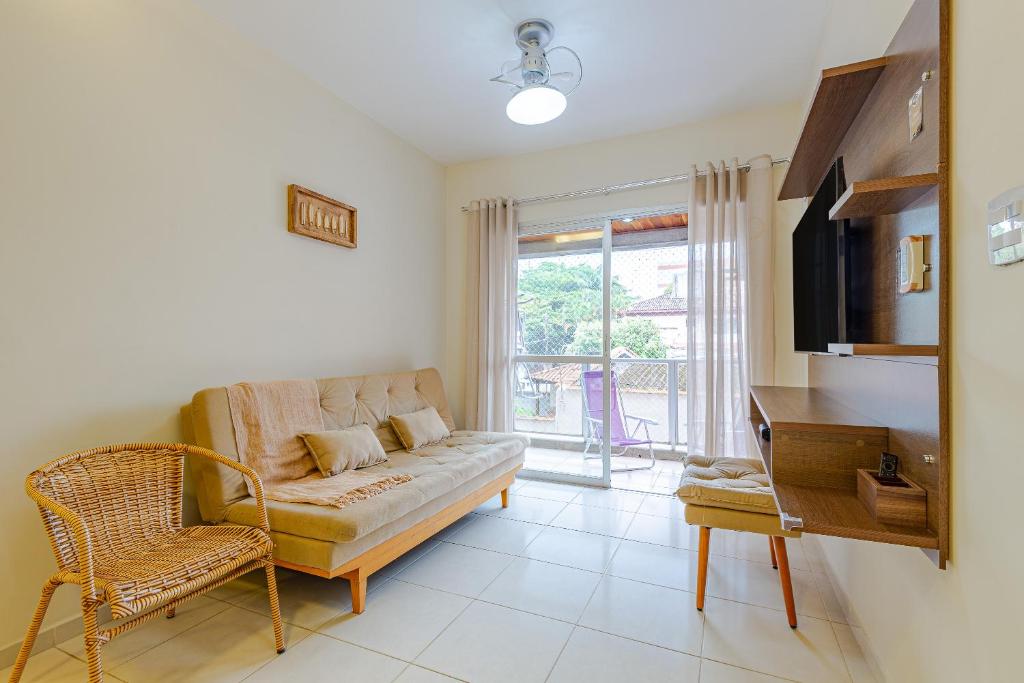 uma sala de estar com um sofá e uma cadeira em Apartamento Praia Enseada - Guarujá no Guarujá